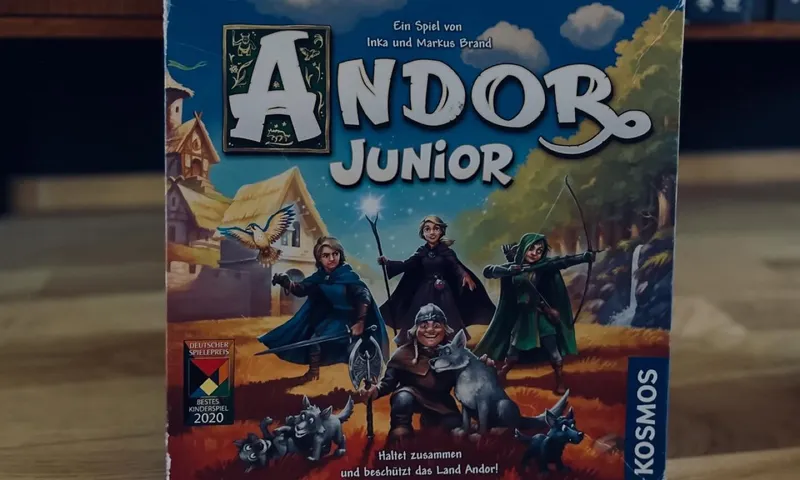 Die deutsche Schachtel von Andor Junior mit Helden und Wölfen auf dem Cover, vor einem Spieleregal