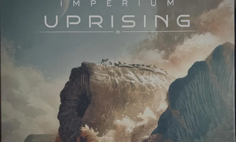 Die Schachtel der deutschen Ausgabe von Dune: Imperium – Uprising mit einem riesigen Sandwurm, der aus der Wüste aufsteigt
