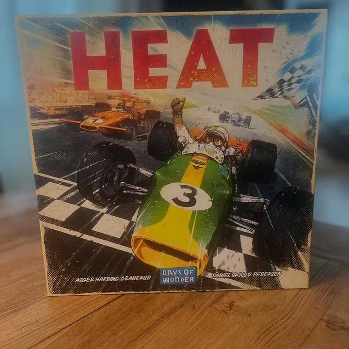 Die Schachtel von Heat steht auf einem Holztisch, auf dem Cover ein Retro-Rennwagen