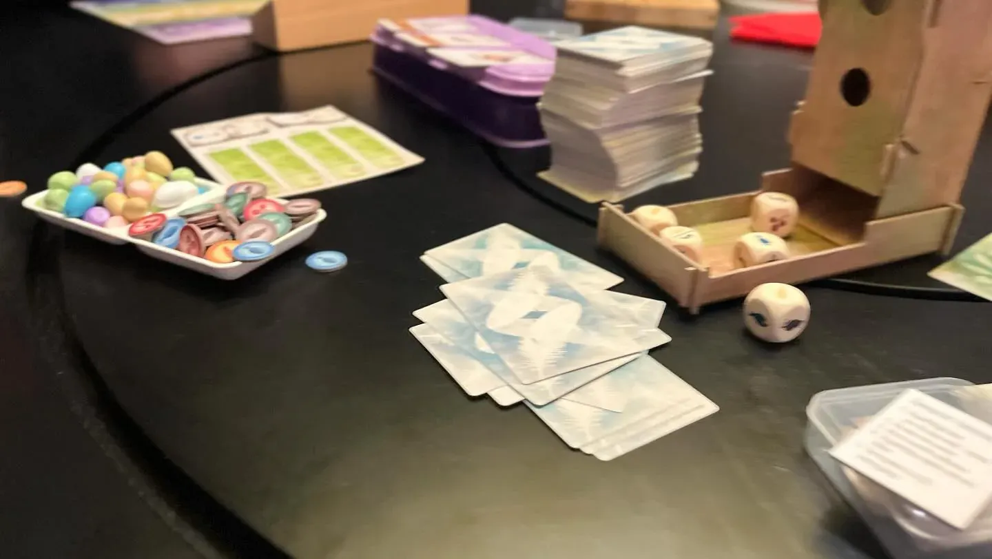 A Wingspan game on a round dark table with the bird feeder