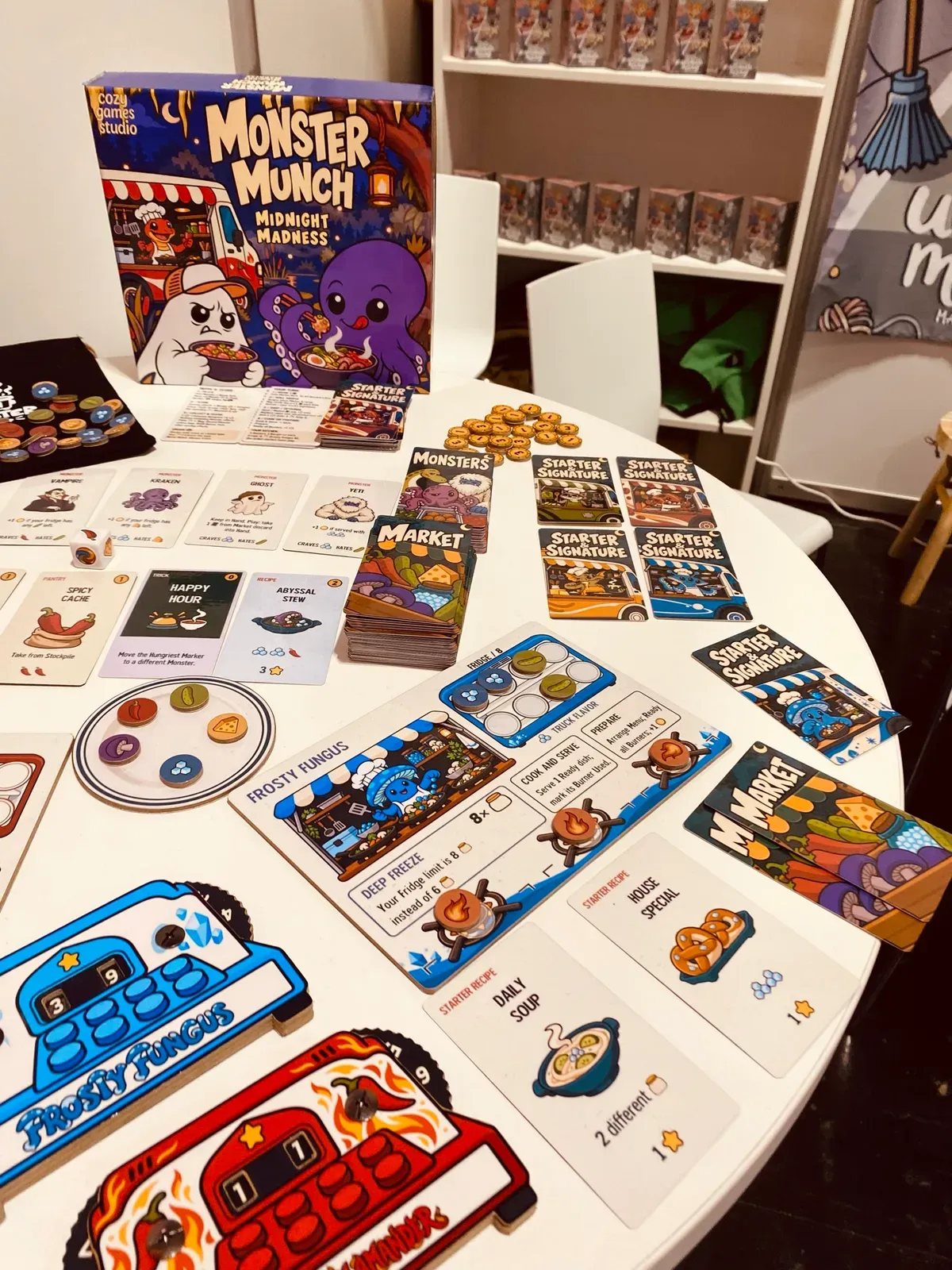 Ein kleiner Verlagsstand mit ausgelegten Karten von Munch: Midnight Madness