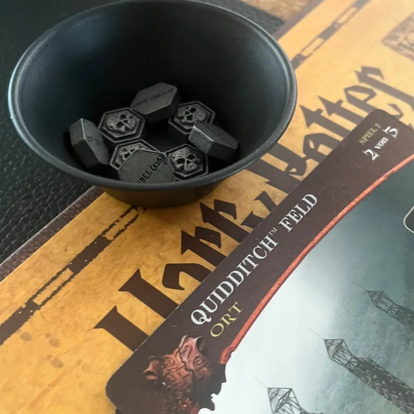 Marker von Kampf um Hogwarts in einer Schale auf dem Quidditch-Spielbrett