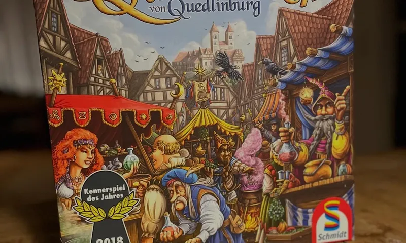 Die deutsche Ausgabe von Die Quacksalber von Quedlinburg auf einem Holztisch, mit dem Kennerspiel-2018-Logo auf der Schachtel