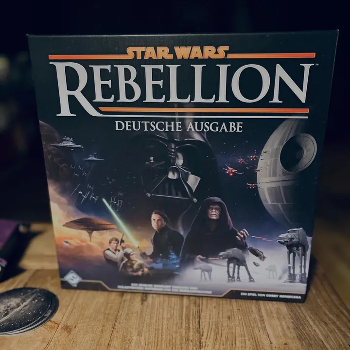 Die Schachtel der deutschen Ausgabe von Star Wars: Rebellion auf einem Holztisch in einem schummrigen Raum